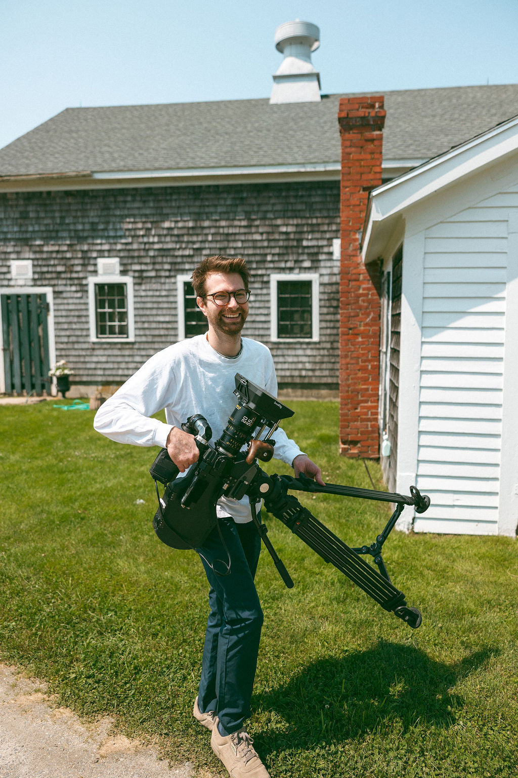 Man holding a camera stabilizer outdoors in front of a house